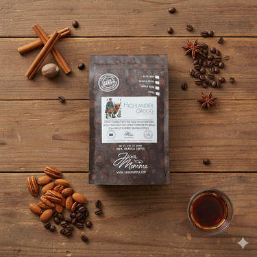Overhead flat lay of Java Momma Highlander Grogg coffee bag on a rustic wood table, styled with cinnamon sticks, nutmeg, star anise, roasted nuts, coffee beans, and a glass of rum — highlighting buttery rum, warm spice, and nutty flavor notes.